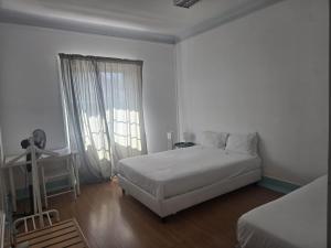 a white bedroom with a bed and a window at Residencial Sky Lounge in Lisbon