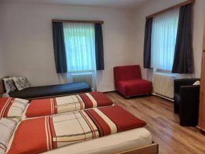a room with two beds and a red chair at Landhaus Fingerhof in Flachau