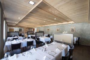 a dining room with white tables and black chairs at Hotel Central in Obersaxen