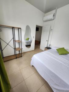 a bedroom with a white bed with a green pillow at Marsella Rest House in Sitio del Niño +25 photos