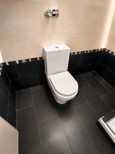 a bathroom with a white toilet and a black tile floor at Alpen Home Room 20 in Kaprun