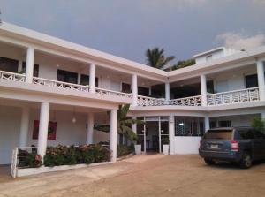a car parked in front of a white building at Sunshine Hotel - Puerto Plata in San Felipe de Puerto Plata