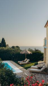 a pool with lounge chairs and an umbrella at Kyanorama Villa, A Seaside Escape in Tragaki
