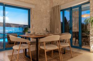 a dining room with a wooden table and chairs at Kyanorama Villa, A Seaside Escape in Tragaki