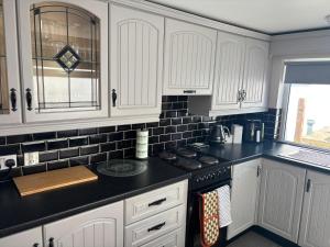 a kitchen with white cabinets and black counter tops at The Millstone in Buncrana