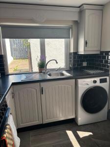 a kitchen with a sink and a washing machine at The Millstone in Buncrana