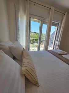a bedroom with a white bed with a large window at BLV Apartments in Tsoukalades