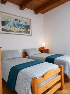 a bedroom with three beds and a painting on the wall at APPARTAMENTO ROEN - Val di Non in Cavareno