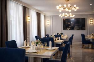a dining room with tables and chairs and a chandelier at South Hotel Tashkent in Tashkent