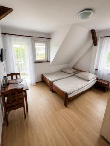 a bedroom with a bed and a table and windows at Pensjonat Rowy Blisko Morza in Rowy
