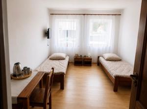 a room with two beds and a table and two windows at Pensjonat Rowy Blisko Morza in Rowy