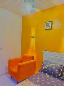 a bedroom with an orange chair and a bed at Résidence kone daouda in Abidjan