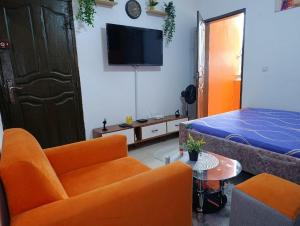 a living room with orange chairs and a bed at Résidence kone daouda in Abidjan