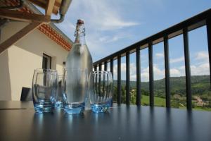 three wine glasses and a bottle on a table on a balcony at Chemin Du Soula in Couiza