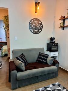a couch in a living room with a clock on the wall at chalé com Hidro e Vista panorâmica para Serra in Paraisópolis