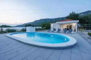 a swimming pool with chairs and a house at Villa Nature in Čapljina