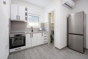 a kitchen with white cabinets and a stainless steel refrigerator at Villa Nature in Čapljina
