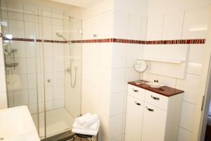 a white bathroom with a shower and a sink at 3C-Appartements in Scharbeutz