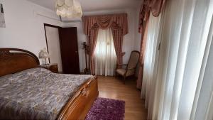a bedroom with a bed and a chair and a window at Grandma Luísa's Corner in Verdelhos