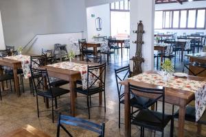 a dining room with tables and chairs with flowers on them at Mundial Parque Hotel in Viçosa