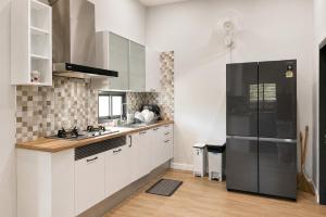 a kitchen with white cabinets and a black refrigerator at Sherlock Home Pool Villa Krabi in Ban Chong Phli