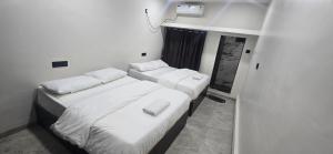 two beds in a room with white walls at Tuljapur Bhaktaniwas in Tuljapur