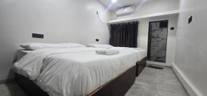 a bedroom with two beds with white sheets at Tuljapur Bhaktaniwas in Tuljapur