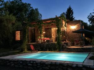 a swimming pool in front of a house at night at Las Pircas, casa de campo in Ciudad Lujan de Cuyo