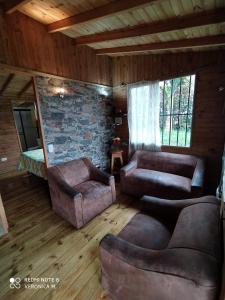 a living room with leather furniture and a stone wall at La Cabaña de Chia in Guarne +1 photo