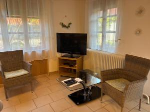 a living room with a tv and two chairs and a table at Horváth Apartmanház in Szigliget