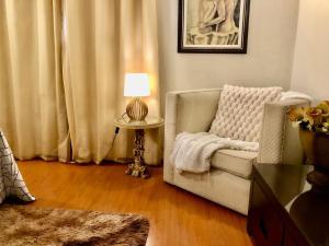 a living room with a chair and a table with a lamp at Chalé do Vale à 10 min de carro de Itacoatiara in Niterói
