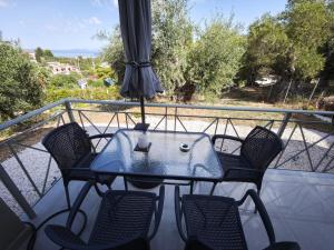 a table with chairs and an umbrella on a balcony at Μπαλκόνι με Θέα in Pérdika