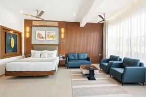 a hotel room with a bed and two blue chairs at Amaari Beach Resort in Kanyakumari +115 photos