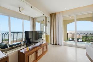 a living room with a television and large windows at Amaari Beach Resort in Kanyakumari