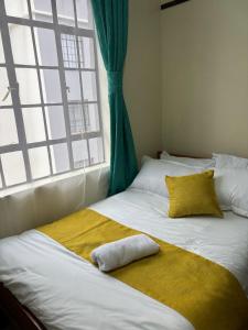 a bed with a yellow blanket and a window at Prestige apartments Machakos in Machakos