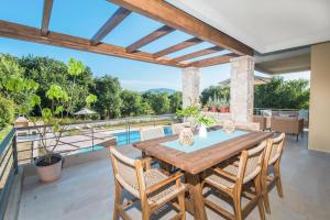 a patio with a wooden table and chairs and a pool at Azure Villa Kanoni in Análipsis