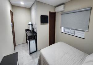 a bedroom with a bed and a window and a desk at Pousada Rainha da Serra in Espirito Santo Do Pinhal