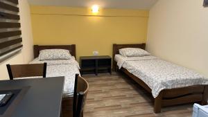 a room with two beds and a table with a desk at Apartmani Kovačević MKM Banja Vrujci in Gunjica