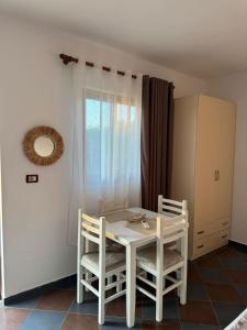 a white table and chairs in a room with a window at N'Gjaci Guest House in Tale +1 photo
