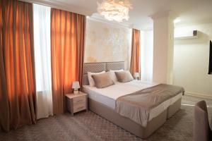 a bedroom with a bed with orange curtains and a chandelier at Gala Terrace Hotel & Restaurant in Baku