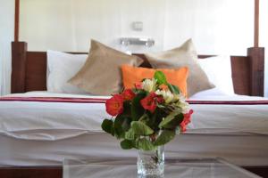 a vase of flowers sitting on a table next to a bed at Mara Son Camp in Maasai Mara National Reserve