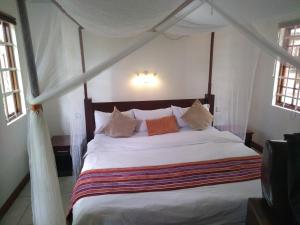 a bedroom with a canopy bed with white sheets and pillows at Mara Son Camp in Maasai Mara National Reserve