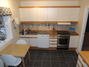 a kitchen with white cabinets and a table and a stove at Tindelykke in Isfjorden