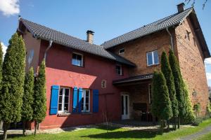 a red brick house with blue shutters and trees at Nie Samym Chlebem in Poborszów