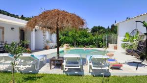 a swimming pool with two chairs and a table at Villa Aura, Kanalia Corfu in Corfu