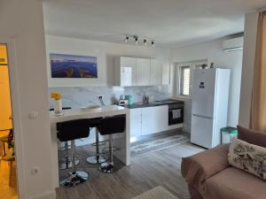 a kitchen with white cabinets and a white refrigerator at Apartman Sanja in Ploče