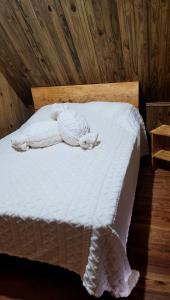 a bedroom with a white bed with a wooden ceiling at Cabanas Brisa da Lagoa in Arroio do Silva