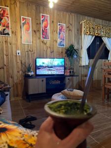 a person holding a bowl of soup in front of a tv at Cabanas Brisa da Lagoa in Arroio do Silva