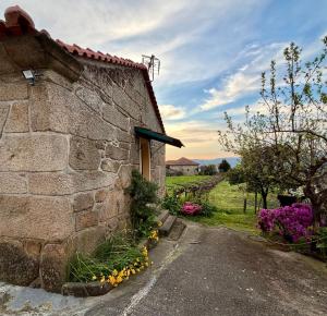 a stone building with flowers in front of it at Casa da Adega in Sá