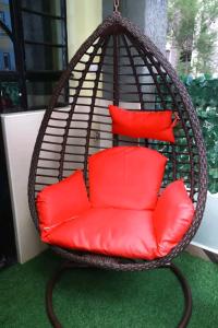 a hanging basket chair with red pillows on a porch at Bulleys BNB in Thika